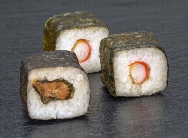 Various sushi dishes on dark grey stone surface