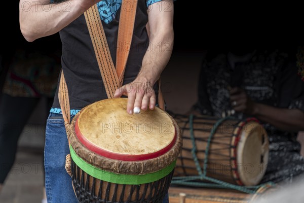 Detail of a djembe drum player in dark back
