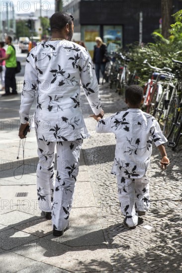 DEU Germany Germany Berlin An African father-and-son team walks along Rudi-Dutschke-Straße wearing the same outfit