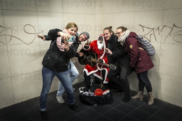 DEU Germany Germany Berlin A dark-skinned singer dressed as Father Christmas plays the guitar in the Stadtmitte underground station