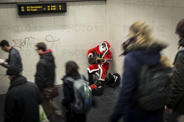 DEU Germany Germany Berlin A dark-skinned singer dressed as Father Christmas plays the guitar in the Stadtmitte underground station