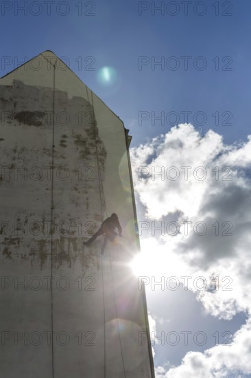 DEU Germany Germany Berlin A worker painting a façade while hanging from a rope