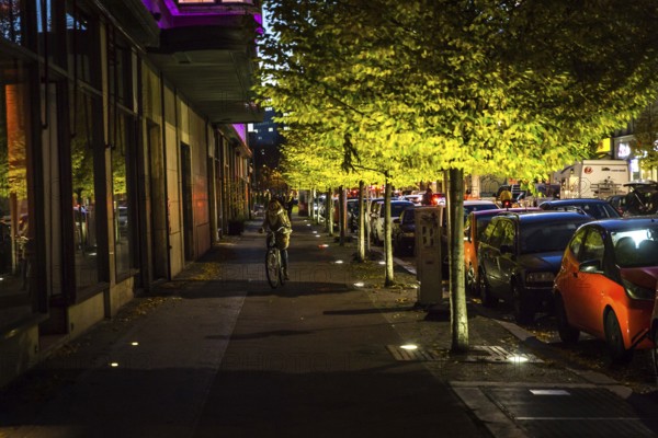 DEU Germany Germany Berlin Cyclist on the footpath in front of the Ellington Hotel in Nürnberger Straße with evening lighting