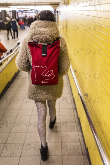 DEU Germany Germany Berlin A woman wears a Berlinale backpack with a plush coat and fishnet stockings through the B-level of Bahnhof Zoo