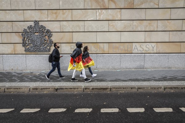 DEU Germany Germany Berlin Two tourists with rain capes in the colours of Germany pass the British Embassy