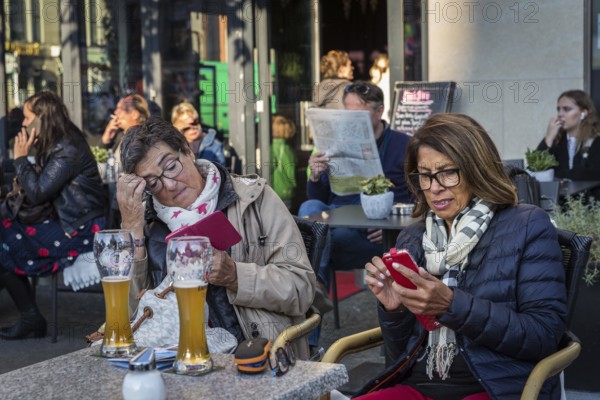 DEU Germany Germany Berlin Guests smoke, talk on the phone, read their mobile phones or look at the newspaper in a café at Gendarmenmarkt