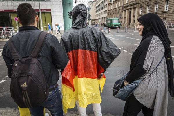 DEU Germany Germany Berlin Two tourists with rain capes in the colours of Germany are accompanied by Muslim friends