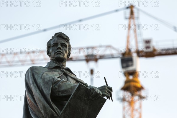 DEU Germany Germany Berlin The statue of the Prussian architect Karl Friedrich Schinkel on Schinkelplatz in Berlin-Mitte. A crane being used for the new palace building in the background