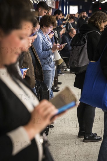 DEU Germany Germany Berlin Passengers look at their mobile phones while waiting for the train at Osloer Straße underground station