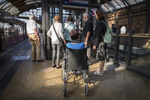 DEU Germany Germany Berlin Disabled tourist in a wheelchair explores Berlin with a city guide. Waiting for the lift at the Hackescher Markt S-Bahn stop