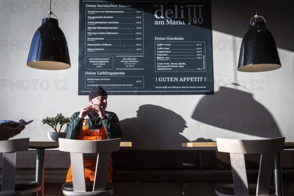 DEU Germany Germany Berlin A man eats a sandwich in a snack bar attached to the Rewe supermarket in Teltow