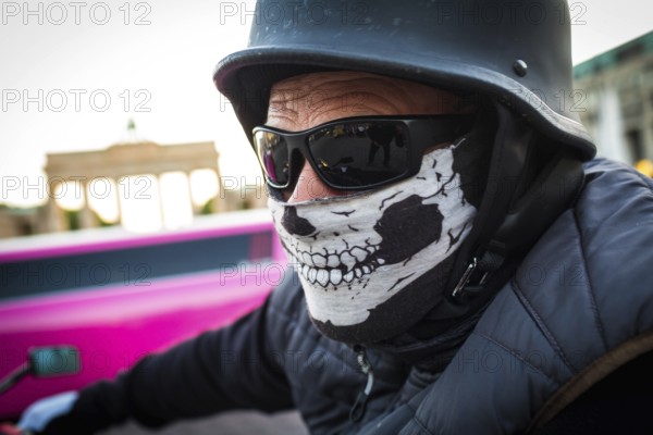 DEU Germany Germany Berlin A motorcyclist with a mask and sunglasses in front of the Brandenburg Tor