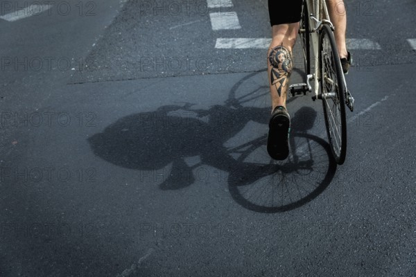 DEU Germany Germany Berlin A huge tattoo adorns the calf of a cyclist just starting out on Potsdamer Platz