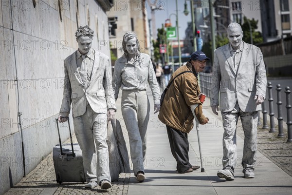 DEU Germany Germany Berlin Three people painted in grey walk along the wall of the Ministry of Finance. A beggar who crosses their path looks after them. A snapshot taken during a photo shoot for the 1000 Gestalten project on Niederkirchner Straße in Mitte