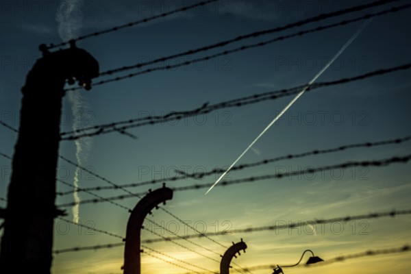 POL Poland Auschwitz Photo series about the memorial site of the former concentration camp Auschwitz-Birkenau. Condensation strips of an aeroplane over the fences of the camp. POL Poland Auschwitz Scenes at the Holocaust Memorial . A planes flies over the camp.Each year more than 2 million visitors are touring through the remains of the former German Nazi concentration and extermination camp Auschwitz-Birkenau. More than 1, 1 million people have been killed here between 1940 and 1945