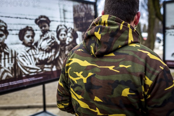 POL Poland Auschwitz Photo series about the memorial site of the former concentration camp Auschwitz-Birkenau. Man with a camouflage jacket watches photos of children of the Holocaust . POL Poland Auschwitz Scenes at the Holocaust Memorial .A man with a camouflage jacket watches a photo exihibition.Each year more than 2 million visitors are touring through the remains of the former German Nazi concentration and extermination camp Auschwitz-Birkenau. More than 1, 1 million people have been killed here between 1940 and 1945