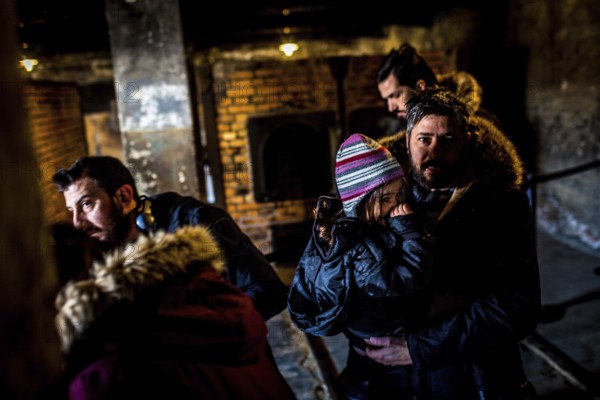 POL Poland Auschwitz Photo series about the memorial site of the former Auschwitz-Birkenau concentration camp. Father and his daughter leaving the oven next to the gas chamber. POL Poland Auschwitz Scenes at the Holocaust Memorial .Father and his daughter leaving the oven next to the gas chamber.Each year more than 2 million visitors are touring through the remains of the former German Nazi concentration and extermination camp Auschwitz-Birkenau. More than 1, 1 million people have been killed here between 1940 and 1945