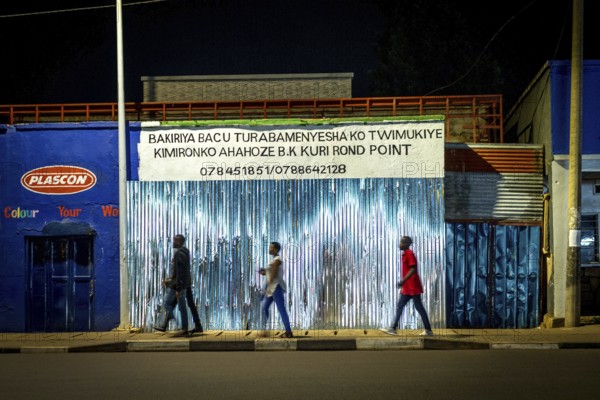 RWA RWANDA Rwanda Kigali people pass closed shops at night