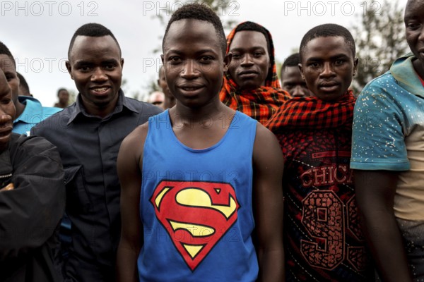 TZA TANZANIA Benaco Young people listen to a nappy salesman in a marketplace. A man in a superman shirt