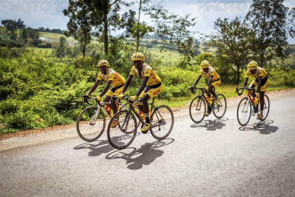 RWA RWANDA Rwanda Gahini cyclists train on a road at Lake Muhazi