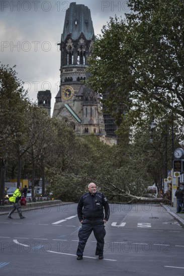DEU Germany Germany Berlin Fire brigade operation on Kurfürstendamm. Storm Xavier had caused trees to fall onto the road. Police officer blocks the road