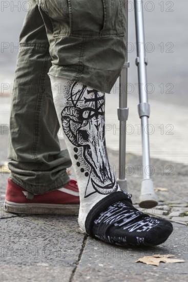 DEU Germany Germany Berlin A man with a painting on his plaster leg waits at a traffic light on Kurfürstendamm. He has shortened one leg of his trousers for better visibility
