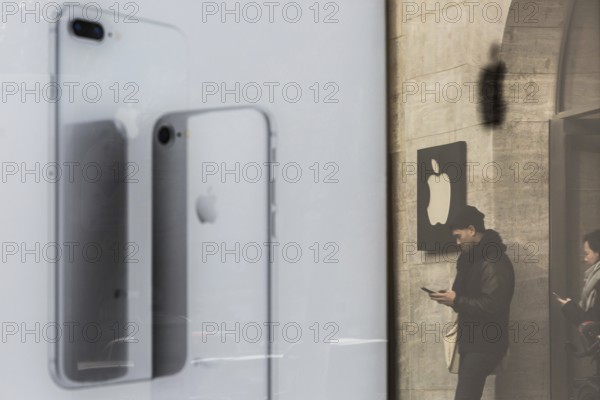 DEU Germany Germany Berlin People with smartphones leave the Applestore on Kurfürstendamm. They are reflected in the outdoor advertising for the new iPhone