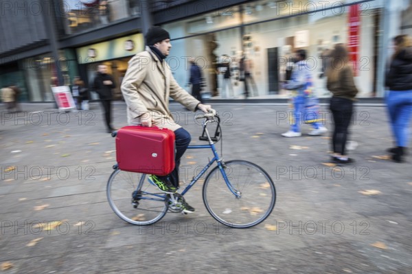 DEU Germany Germany Berlin A cyclist rides with a suitcase on the pavement