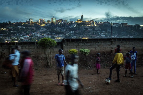 RWA RWANDA RUANDA Kigali Children playing football on a dusty path In the background, the Kiyovu banking district