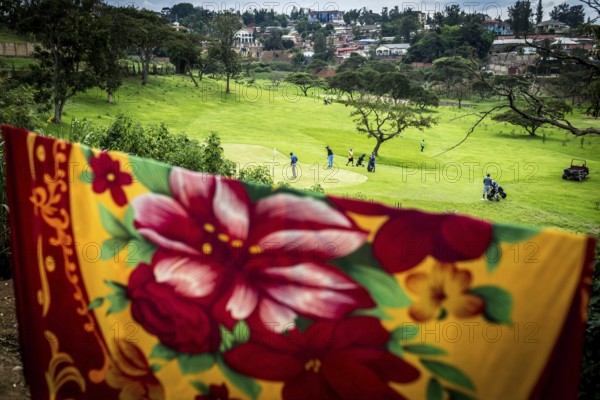 RWA RWANDA RUANDA Kigali Rwandans play on a centrally located golf course at lunchtime. The ceiling belongs to residents of neighbouring huts