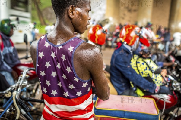 RWA RWANDA RUANDA Kigali Taxi drivers with motorbikes and bicycles wait under a bridge for the end of a rainstorm