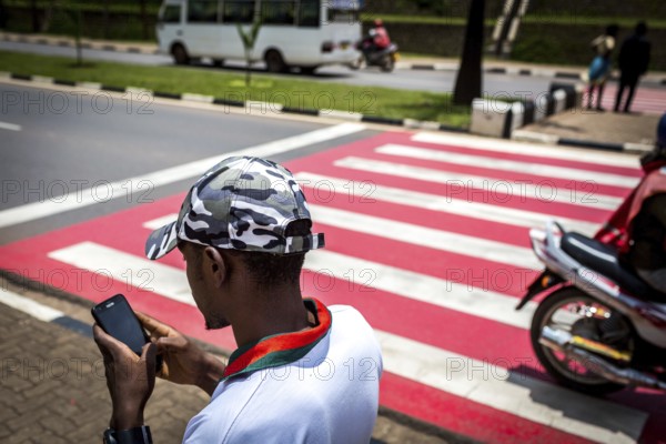 RWA RWANDA RUANDA Kigali A youth with a camouflage baseball cap looks at his mobile phone while walking along the street