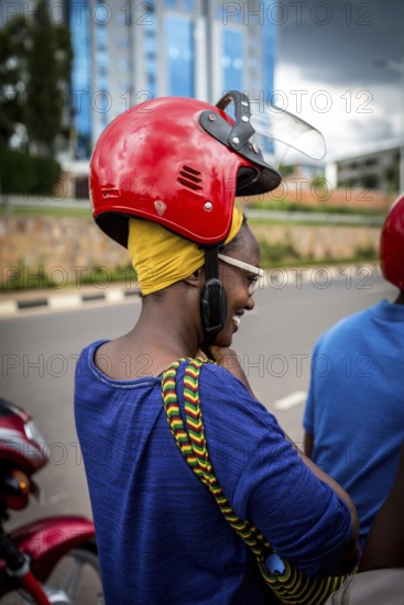 RWA RWANDA RUANDA Kigali A woman with a high hairstyle locks her helmet in front of taking a taxi on a motorbike