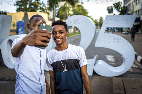 RWA RWANDA RUANDA Kigali People take a photo of themselves at the sign commemorating the genocide in the Kiyovu banking district