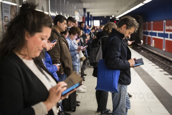 DEU Germany Germany Berlin Passengers look at their mobile phones while waiting for the train at Osloer Straße underground station