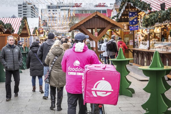DEU Germany Germany Berlin A Foodora food courier rides his bike through the Christmas market on Breitscheidtplatz
