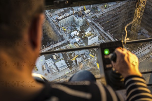 DEU Germany Germany Berlin A crane operator is transporting building materials on a construction site. He is sitting at a height of 60 metres