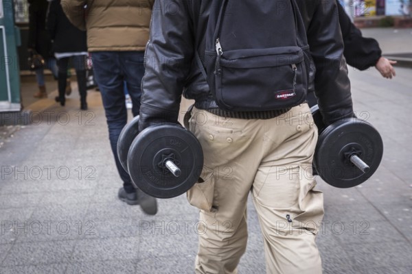 DEU Germany Germany Berlin A man carries two dumbbells in his hands on his way to the underground station