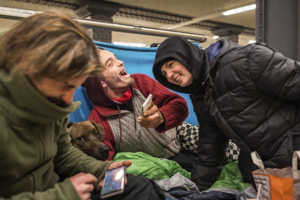 DEU Germany Germany Berlin Homeless people spend the night in a passageway at Lichtenberg underground station. Like Moritzplatz, the station has been made available for overnight stays by the BVG during the winter months.homeless people with their smartphones