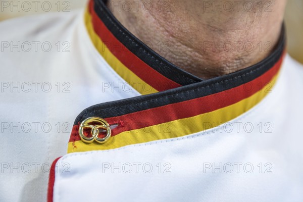 DEU Germany Germany Berlin Scene of the Green Weeks, the annual trade fair for food, agriculture and ecology. A baker with a collar in the German colours and a golden pretzel