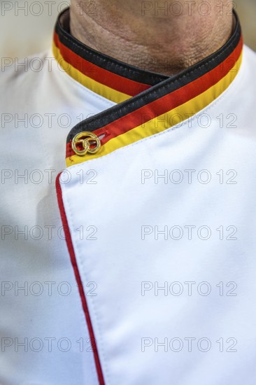 DEU Germany Germany Berlin Scene of the Green Weeks, the annual trade fair for food, agriculture and ecology. A baker with a collar in the German colours and a golden pretzel