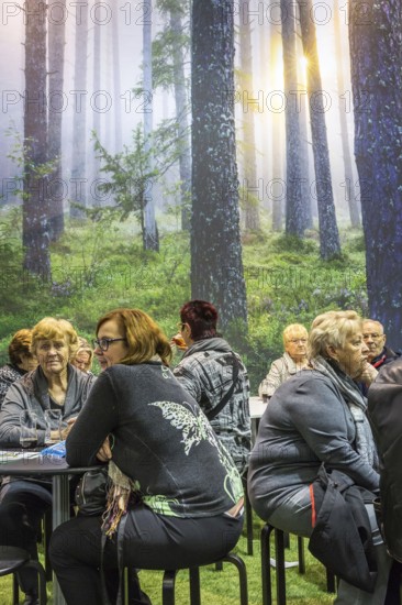 DEU Germany Germany Berlin Scene of the Green Weeks, the annual trade fair on food, agriculture and ecology. Visitors take a break in front of a photo wall with forest