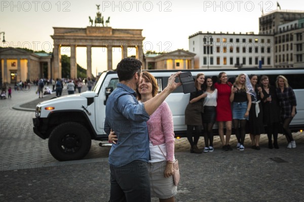 DEU Germany Germany Berlin Young woman pose with a rented stretch limousine in front of the Brandenburg Tor, where a couple takes a selfie