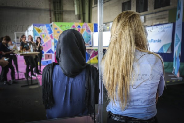 DEU Germany Germany Berlin As part of the German Foundation Week, the Cologne-based organisation Rheinflanke demonstrates sports facilities for refugees in the hangar at Tempelhof Airport. Audience member with headscarf next to blonde woman