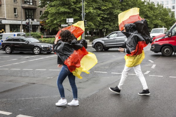 DEU Germany Germany Berlin Two tourists with rain capes in the colours of Germany while sight seeing