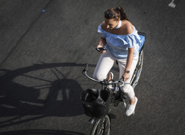 DEU Germany Germany Berlin Scene with cyclists on Schlossstraße in Steglitz. Woman with mobile phone while riding