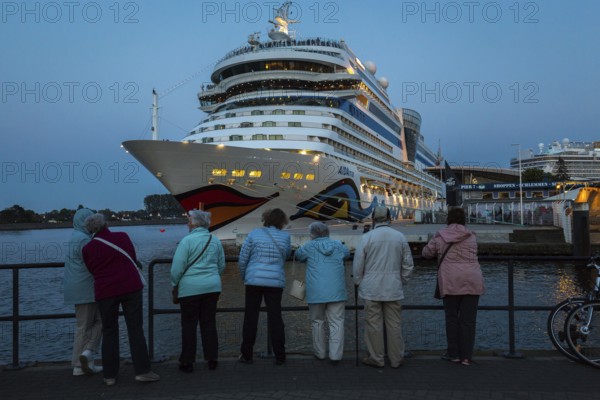 DEU Germany Germany Warnemünde Scene on the beach of Warnemünde with a large harbour for cruise ships on the Baltic Sea. Visitors admire the Aida