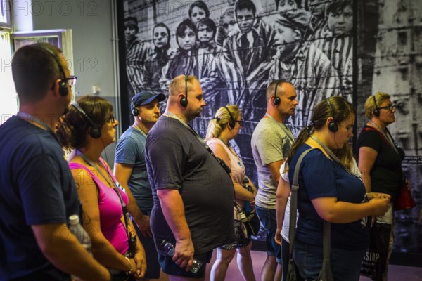 POL Poland Poland Auschwitz visitors in a barrack in front of a photograph of children at the memorial site of the former Auschwitz concentration camp