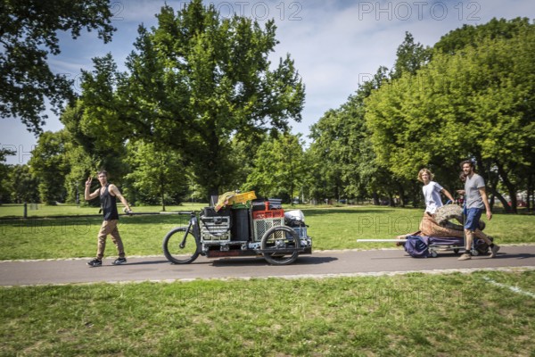DEU Germany Germany Berlin Young men transporting technology for an event through Volkspark Friedrichshain