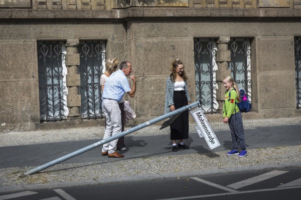 DEU Germany Germany Berlin A man shows a strong arm while a schoolgirl looks at a knocked down street sign in Mohrenstraße